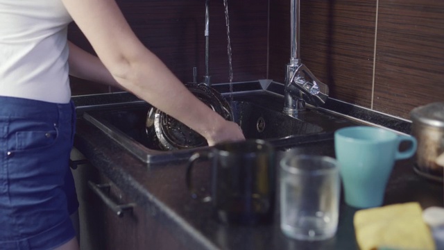 在厨房里洗盘子的女人。视频素材