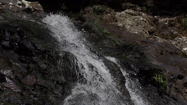 瀑布从上面流下的水花。岩石表面和水流的对比很美。视频素材