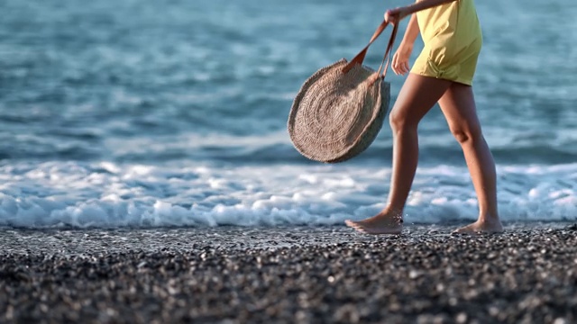 女性的腿走在海滩与海浪在日落慢动作。用RED摄像机拍摄4K视频素材