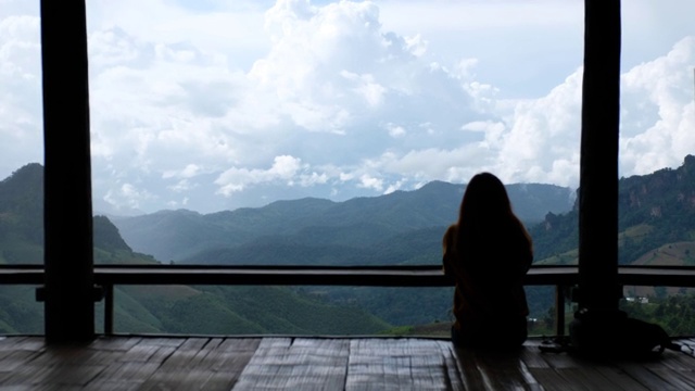 后视图一位女性旅行者坐着，看着一个美丽的山和自然景观视频素材