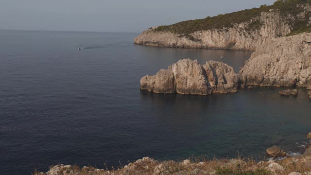 海岸线有蓝色的海湾和陡峭的岩石峭壁。海滩在阳光明媚的一天，意大利视频素材