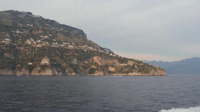 沿海有山，山坡有村。摩托艇漂浮在岩石海岸，意大利视频素材