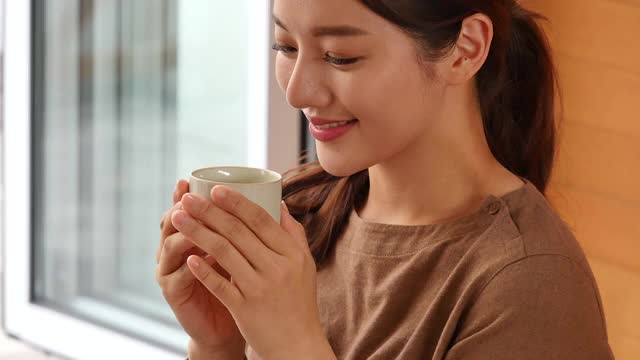 茶道——年轻女子端着茶杯，闻着茶视频素材