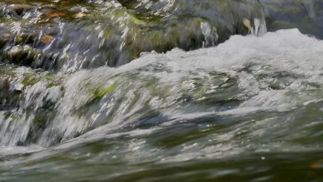 清澈的水冲过岩石的河流的特写。视频素材