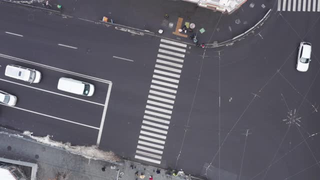 汽车和行人在城市十字路口附近的人行横道上行驶，无人机在上空拍摄视频素材