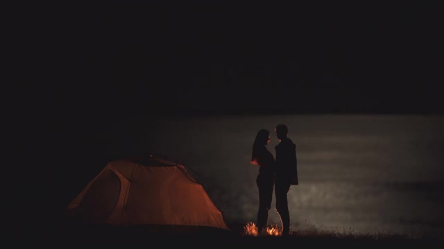 那对年轻夫妇在夜晚的营地里手牵着手聊天视频素材