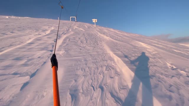 滑雪场滑雪板被t形杆牵引上山。滑雪板使用与滑雪缆车在山区度假村，POV。野生的滑雪胜地。强烈的风。视频下载