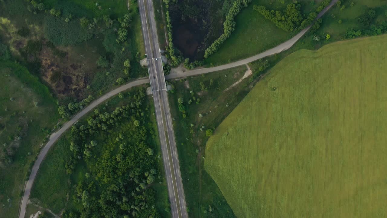 初夏的绿色田野和穿过的道路鸟瞰图视频素材