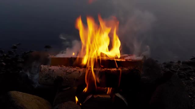 篝火在夜晚被黑暗包围时燃烧着炽热的橙色和黄色。关闭了。视频素材