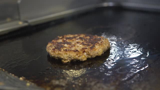 为芝士汉堡烹制牛肉和猪肉馅饼。肉在厨房烤。油滴，烟雾缭绕。视频素材