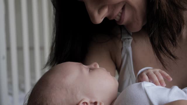 年轻的白人妇女亲吻她的新生儿的头和手的特写视频素材