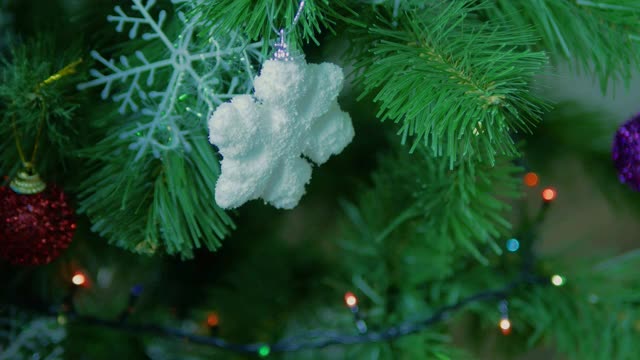 装饰圣诞树，一个男人把一个玩具挂在新年的树上。视频素材