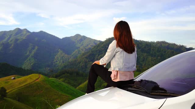 年轻女子坐在车上看美丽的山景，而驾驶公路旅行的假期视频素材