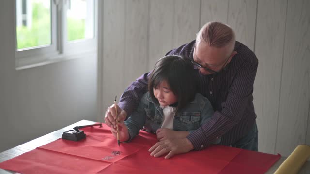 亚洲华人小女孩向她的祖父学习写中国书法视频素材