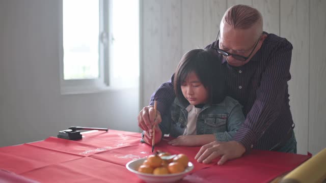 亚洲华人小女孩向她的祖父学习写中国书法视频素材