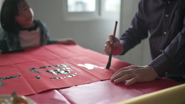 亚洲华裔年轻女孩帮助和学习她的祖父写中国书法视频素材