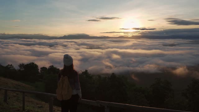 年轻女子旅行者在早晨看日出和山上的雾海，旅行的生活理念视频素材