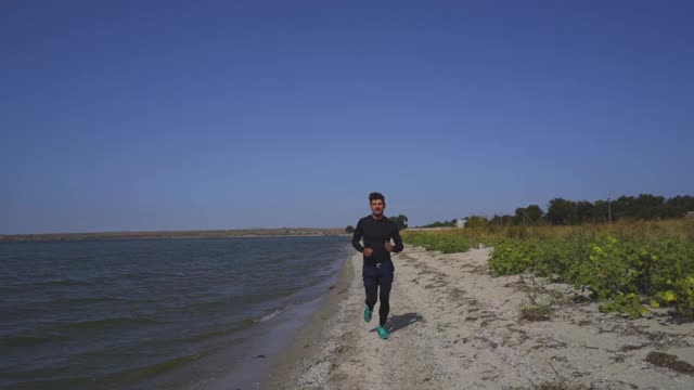 沿着海岸线跑步的帅哥。慢动作视频素材