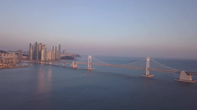 日落时，韩国釜山海云大谷的光大公桥上的海洋城市摩天大楼和汽车运动视频素材