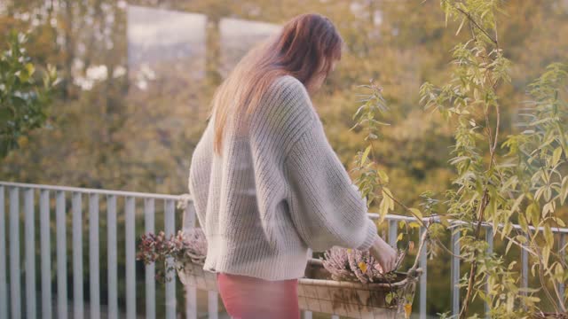 在她的阳台上，在植物间挥手的女人视频素材