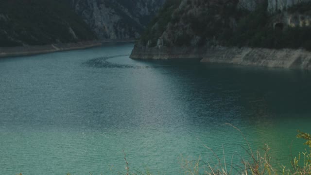 快乐的女游客带着一个大背包跑到山顶，考虑一个美丽的山，湖和山。提出了高手中。晚上日落。后视图视频素材