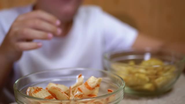 小孩的手从盘子里拿薯条，饼干。吃有害的零食视频素材