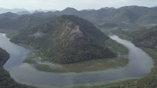 从空中俯瞰里耶卡克诺耶维察。河流蜿蜒绕山，风景秀丽，绿树成荫的山谷，风景如画。美丽的山在地平线上。天空倒映在河里视频素材