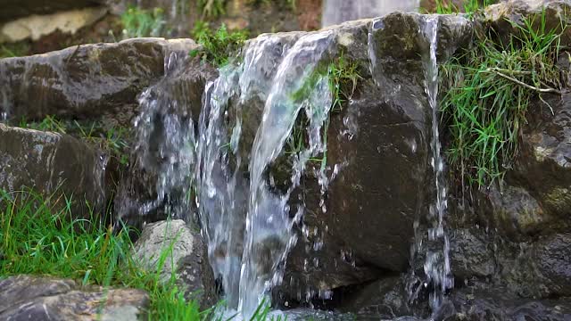 瀑布带着石头和绿草奔流而下视频素材