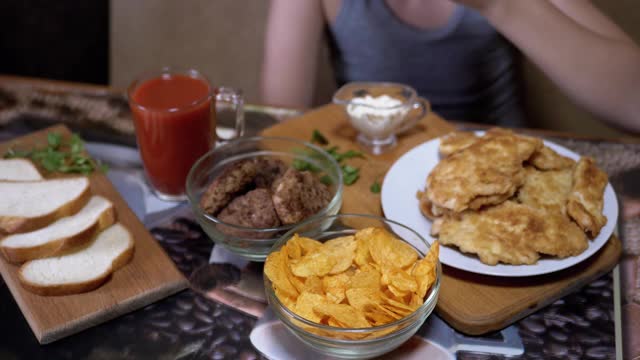 饥饿的小手从盘子里拿起脆脆的金色薯片。晚餐中的垃圾食品视频素材