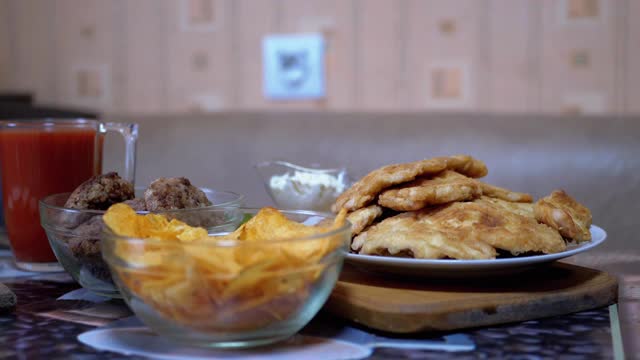 饥饿的男孩从桌子下的手在没有人看到的时候从盘子里拿走了薯片视频素材