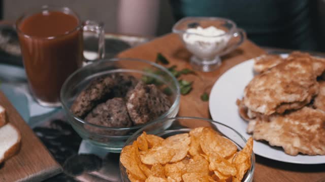 饥饿的小手从盘子里拿起脆脆的金色薯片。晚餐中的垃圾食品视频素材