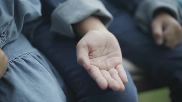 小男孩和小女孩手牵着手的特写。一对认不出来的白人小孩坐在户外。统一和初恋的观念视频素材