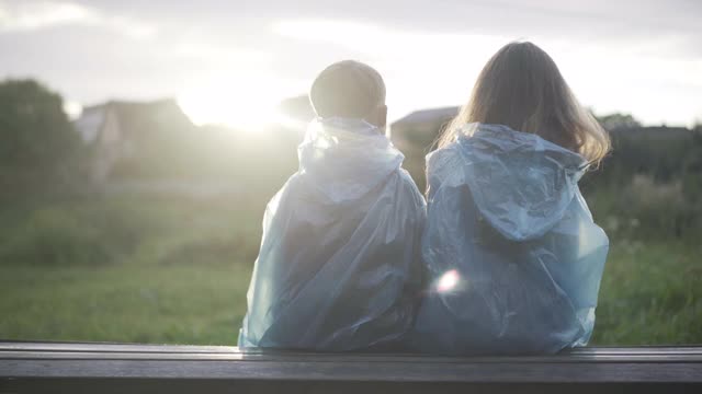 背景的孩子拥抱在阳光下欣赏夏天日落在雨天。快乐轻松的白种男孩拥抱着女孩。浪漫的约会和初恋的概念视频素材