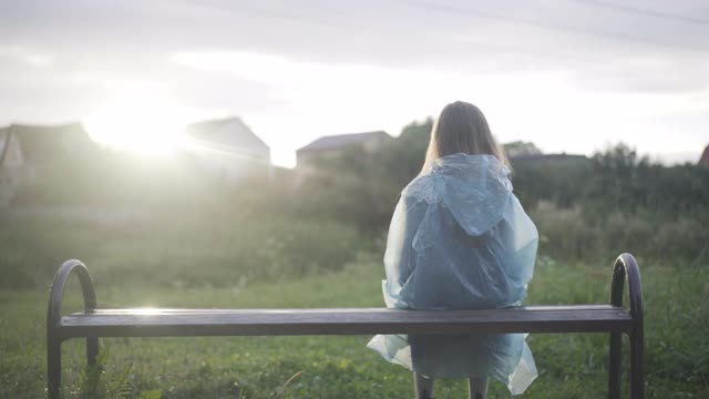 小男孩和女孩一起坐在阳光下的长椅上。在阴雨的夏天，在户外欣赏日落的高加索朋友的背影。团结和友谊视频素材