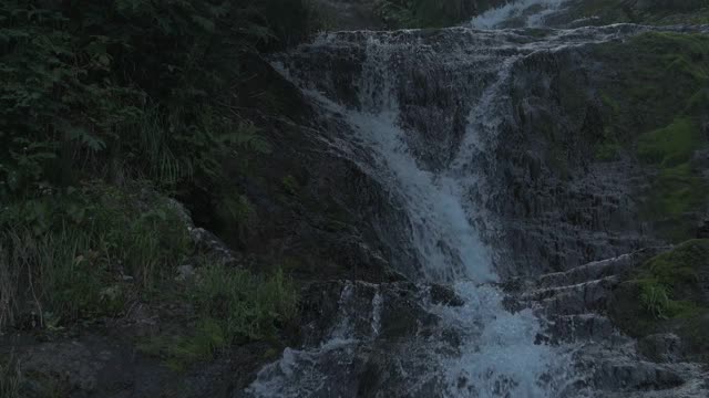 在热带森林中，瀑布从布满岩石的、长满苔藓的巨石上冲下。视频素材