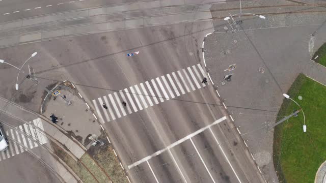 汽车和行人在城市十字路口附近的人行横道上行驶，无人机在上空拍摄视频素材