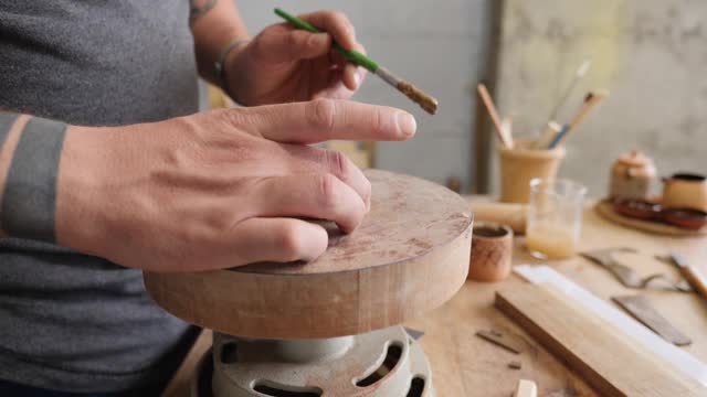 陶工用水刷湿润部分，把它粘到底座上。陶瓷艺术的概念。手工制作的陶器视频素材