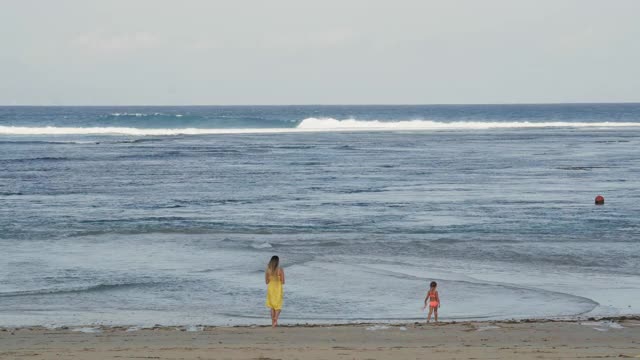 年轻的妇女和孩子沿着海岸行走视频素材