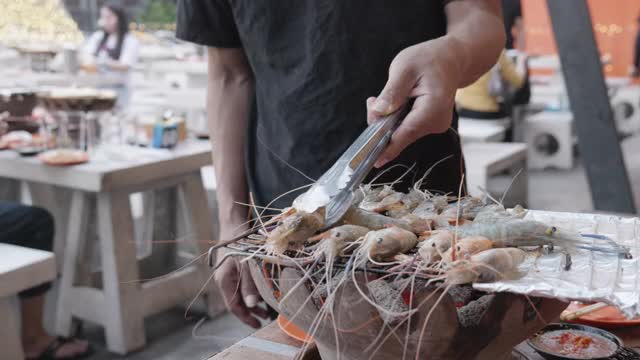 40-50岁的亚洲男性配以著名的海鲜泡芙烧烤，在泰国街头广受欢迎的海鲜美食。视频素材