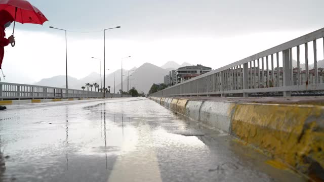 一个人穿着红色雨衣，拿着雨伞走在街上视频素材