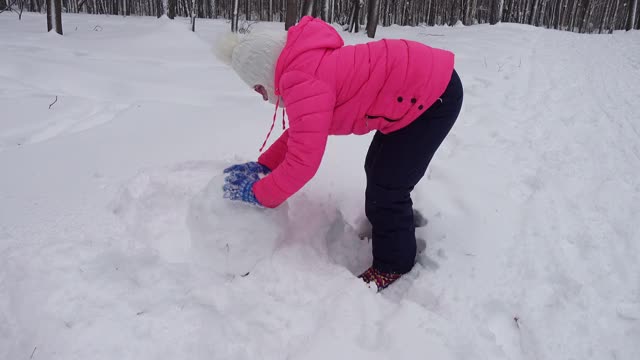 小女孩在冬天的森林里堆雪人视频素材