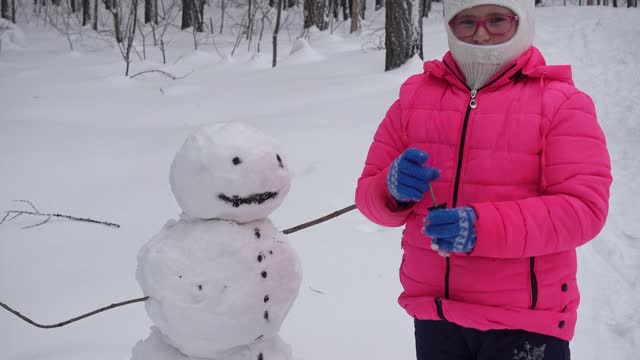 小女孩在冬天的森林里堆雪人视频素材