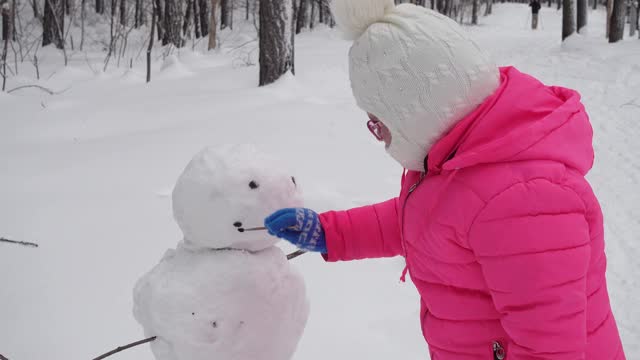 小女孩在冬天的森林里堆雪人视频素材