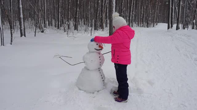 小女孩在冬天的森林里堆雪人视频素材