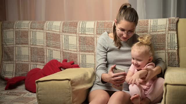 一位年轻的孕妇和她的小女儿给亲戚们打视频电话视频素材