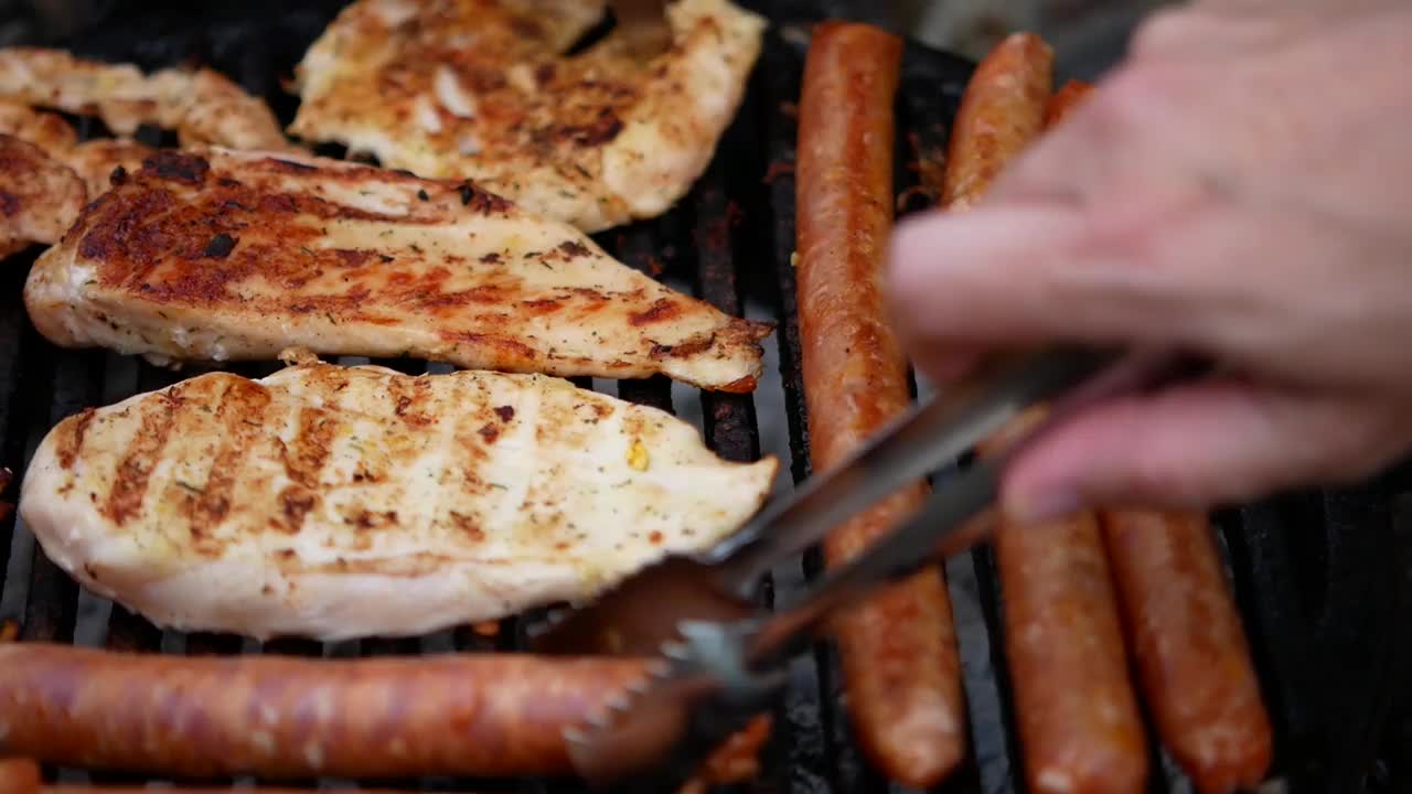 在院子里的烤架上烤着肉和香肠，烤鸡和香肠视频素材