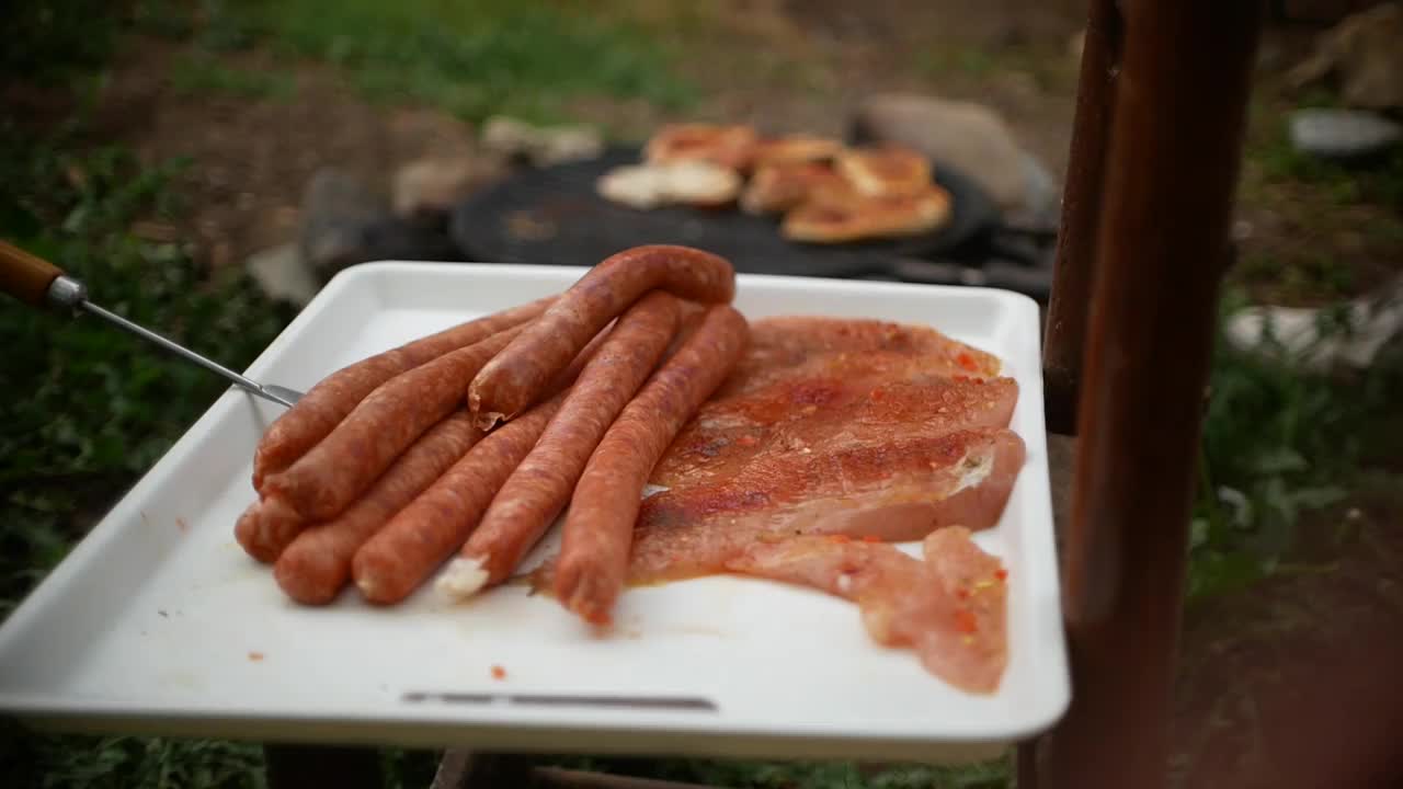 在院子里的烤架上烤着肉和香肠，烤鸡和香肠视频素材