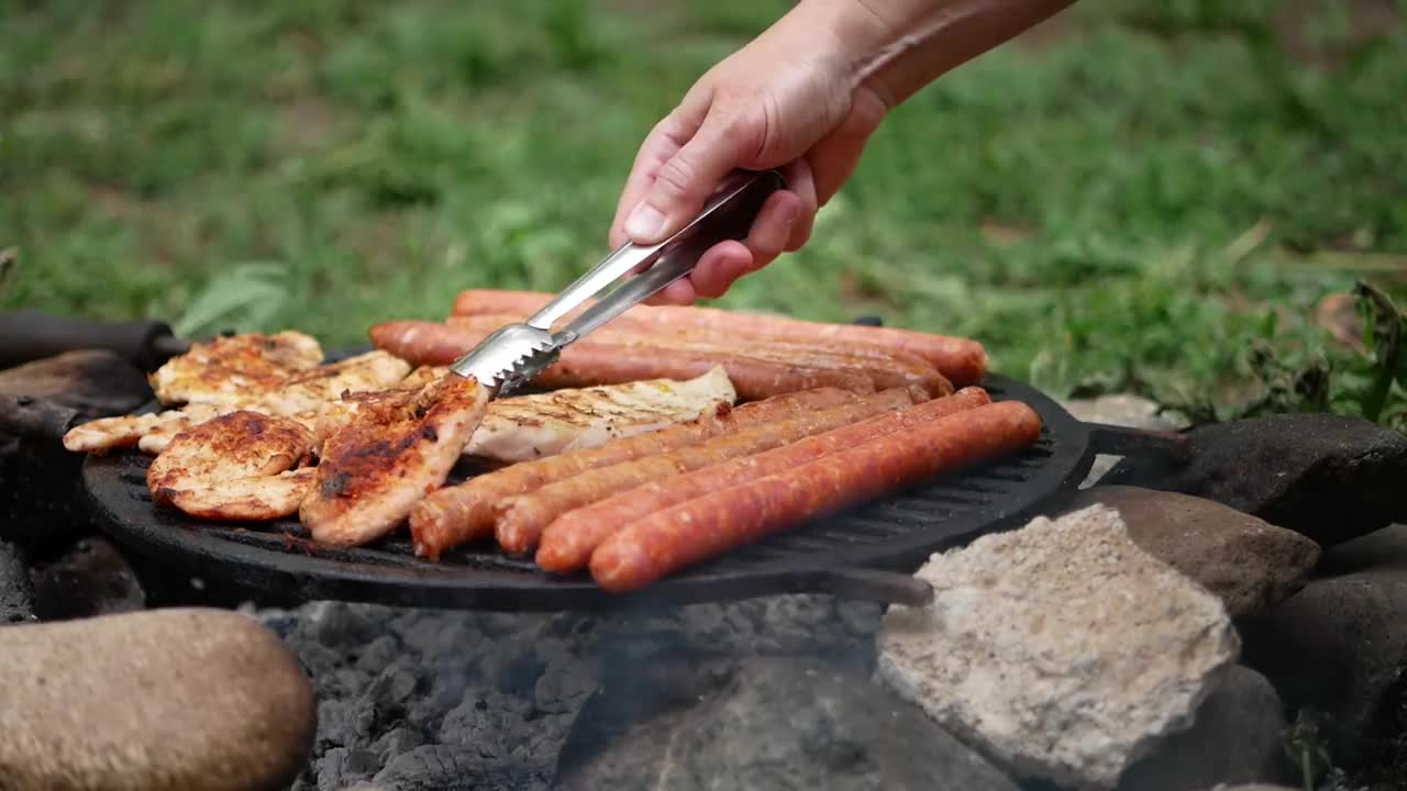 在院子里的烤架上烤着肉和香肠，烤鸡和香肠视频素材