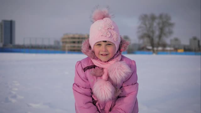 穿着粉红色衣服的有趣小女孩在冬天吐雪视频素材