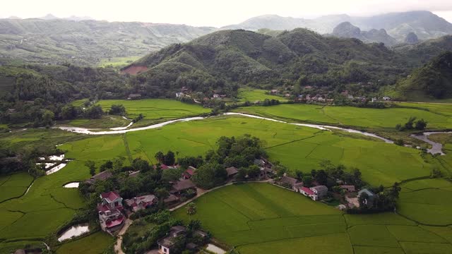 风景如画的鸟瞰图，绿色的稻田与小村庄和山丘。视频素材